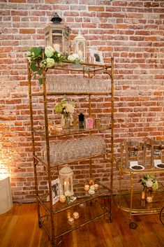 a shelf with candles and flowers on it in front of a brick wall at a wedding