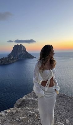 a woman standing on top of a cliff next to the ocean