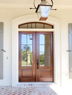 the front entrance to a home with two double doors and brick pavers flooring