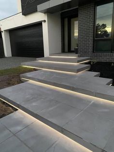 some steps that have been lit up in front of a house with garage doors and windows