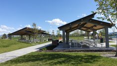 an outdoor pavilion with picnic tables and benches on the grass next to trees in front of it