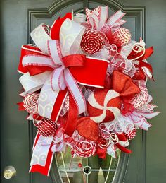 a red and white christmas wreath with candy canes hanging on a front door handle