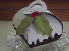 an ornament with holly leaves on it sitting on top of some ice cubes