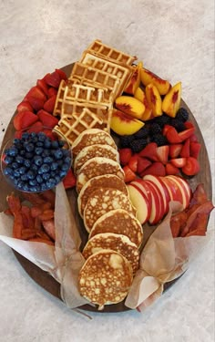 a platter with pancakes, fruit and waffles on the side is shown