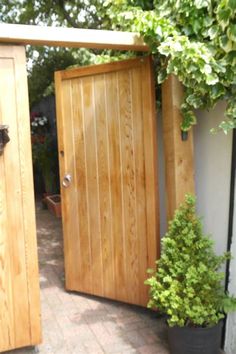 two wooden doors are open on the side of a house next to a potted plant