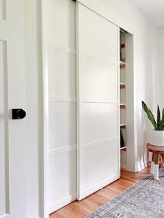 the interior of a home with white closet doors and wood flooring, along with an area rug