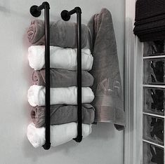 a towel rack with five towels hanging on it's side in a green bathroom