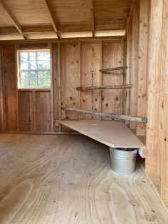 an empty room with wood paneling and a metal bucket on the floor in front of it