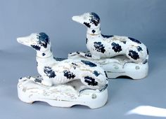 two ceramic ducks sitting next to each other on top of a white surface with black spots