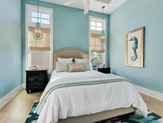 a bedroom with blue walls, white bedding and seahorse artwork on the wall