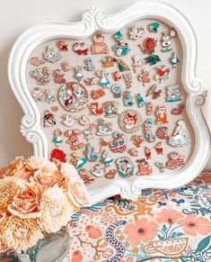 an ornate white frame holds several different types of earrings and flowers in front of a floral bouquet