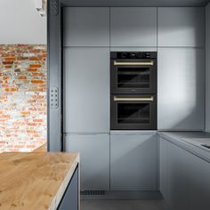 a kitchen with two ovens and a counter top next to a brick walled wall