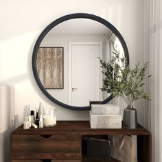 a round mirror on the wall above a dresser with candles and a plant in it