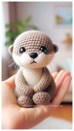 a small crocheted otter is sitting on someone's hand