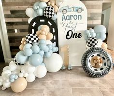 balloons and cars are on display in front of a sign that says aaron is first one