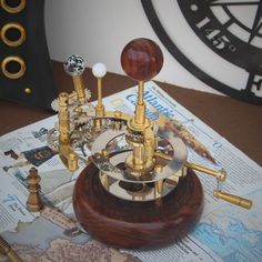 there is a clock made out of wood and brass parts on top of a map