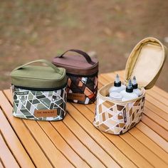 two small containers sitting on top of a wooden table next to an open bag with bottles in it