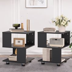 two black end tables with books on them and a vase full of flowers in the corner