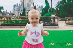 a baby girl standing in front of a castle