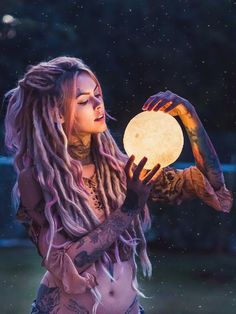 a woman with dreadlocks holding a moon in her hand