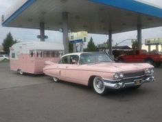 an old pink car parked in front of a gas station