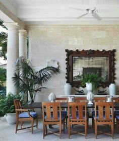 a dining room table with blue chairs and potted plants