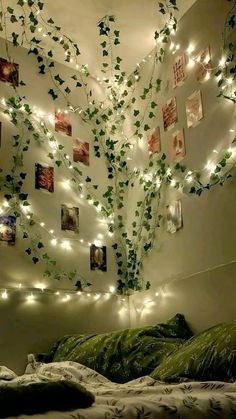 a bedroom decorated with lights and pictures on the wall above the bed is lit up by string lights