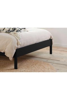 a bed sitting on top of a wooden floor next to a white and black blanket