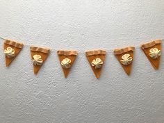 a string of paper decorations hanging on a wall next to a white wall with an orange triangle