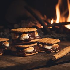 some cookies and marshmallows are stacked on top of each other in front of a fire