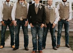 a group of men standing next to each other in front of a white building wearing vests and ties