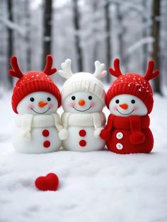 three snowmen wearing red hats and scarves are standing in the snow with one another