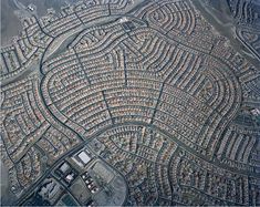 an aerial view of a city with lots of houses and roads in the middle of it