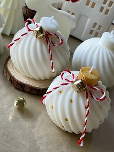 two white christmas ornaments sitting on top of a table next to other decorations and bells