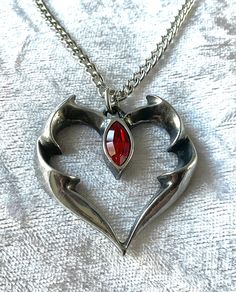 "Swift, silent and breathless, the almost imperceptible kiss of the vampire hypnotically seduces the victim into a passionate night of love and lust. A 1 ¼\" long pewter pendant heart -shaped outline formed of bat's wings, and set centrally with a red Austrian crystal. The pendant comes with a velvet gift pouch. Made by Kiss of a red rose with help from Alchemy England 1977." Vampires Kiss, Vampire Necklace, Vampire Jewelry, Vampire Kiss, Gothic Pendant, Pendant Heart, Pewter Pendant, Love And Lust, Buy Necklace