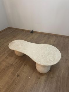 a white bench sitting on top of a hard wood floor next to a black bird