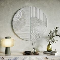 a white table topped with a vase filled with flowers next to a wall mounted mirror