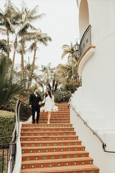 a bride and groom walking down the stairs at their wedding ceremony in palm trees,