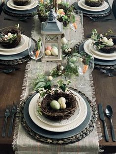 the table is set with plates, silverware and eggs in nests on them