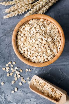 oatmeal in a wooden bowl next to two stalks of wheat on a gray surface