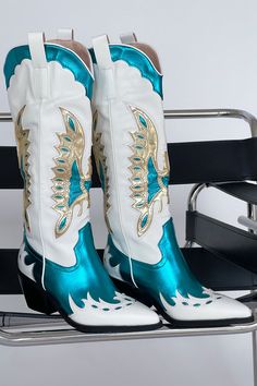 The cowgirl boots of your dreams just landed! The Azalea Wang Apolline Green Metallic Western Boot is a knee-high statement cowboy boot. Step out in style with this high-impact embroidered western boot. Featuring a white body with teal and gold metallic overlay details, and a black sole. Pair these boots with a cute mini dress for the perfect main character energy look! Details: black block heel closed pointed toe structured upper slip on design western inspired embroidery side pull tabs synthet Teal Cowgirl Boots Outfit, Metallic Western Boots, Country Costume, Country Costumes, Metallic Overlay, Mode Country, Main Character Energy, Bota Country