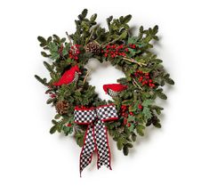 a christmas wreath with pine cones and red ribbon hanging on a white wall next to a black and white checkered bow