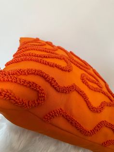 an orange decorative pillow on white fur