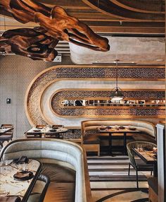 the interior of a restaurant with tables, chairs and artwork hanging from the ceiling above