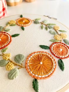 an embroidery project with oranges and green leaves on the hoop next to some pumpkins