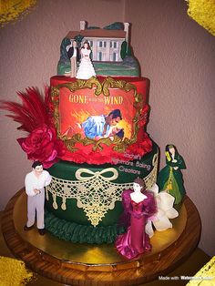 a three tiered cake decorated with figurines and an advertisement on the top