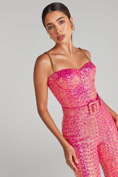 a woman in pink sequin jumpsuits posing for the camera with her hand on her hip