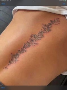 the back of a woman's thigh with flowers on it and leaves coming out