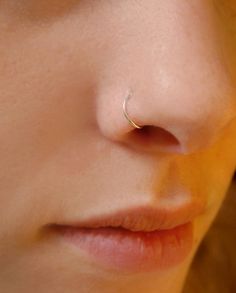 a close up of a woman with a nose piercing on her left side, looking at the camera