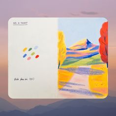 an open notebook with colored pencils on the pages and mountains in the back ground